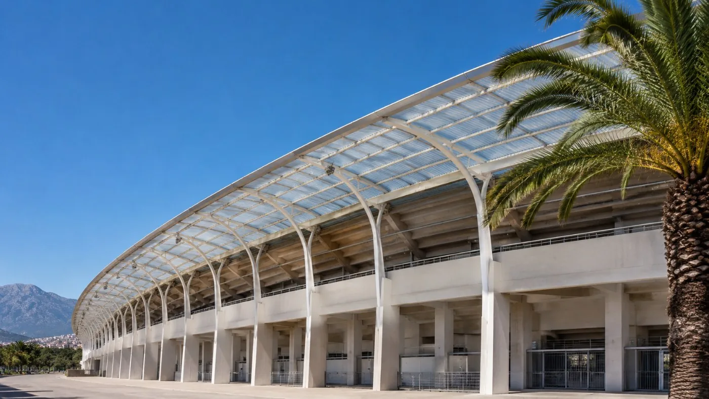 Die gekrümmte weiße Betontribüne und das durchscheinende gerippte Dach eines Stadions aus den 1970ern in starker Sonne